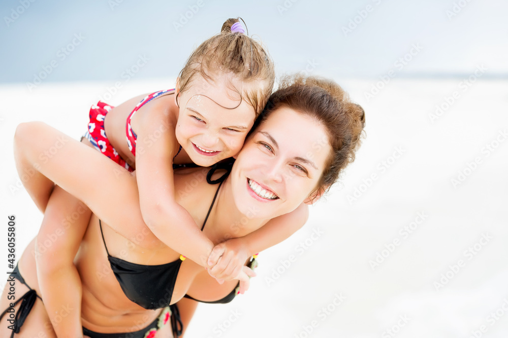 Happy mother and little daughter having fun on sand beach on Maldives at summer vacation. Family on the beach concept.