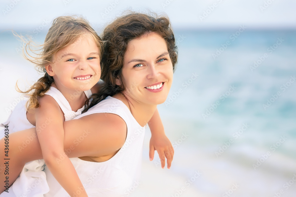 Portrait of happy mother and little daughter on ocean beach on Maldives at summer vacation. Family on the beach concept.