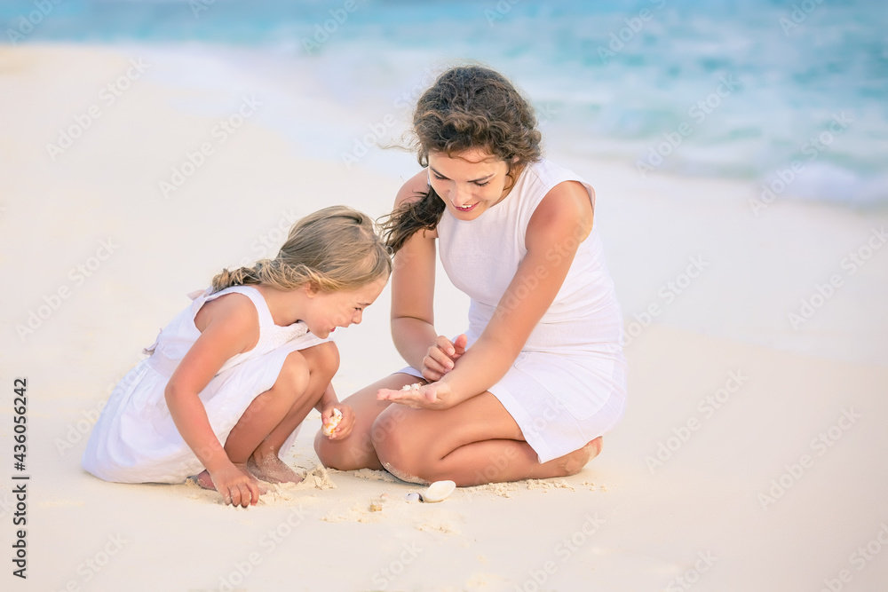 Mother with little daughter playing on ocean beach, Maldives. Family on the beach concept.