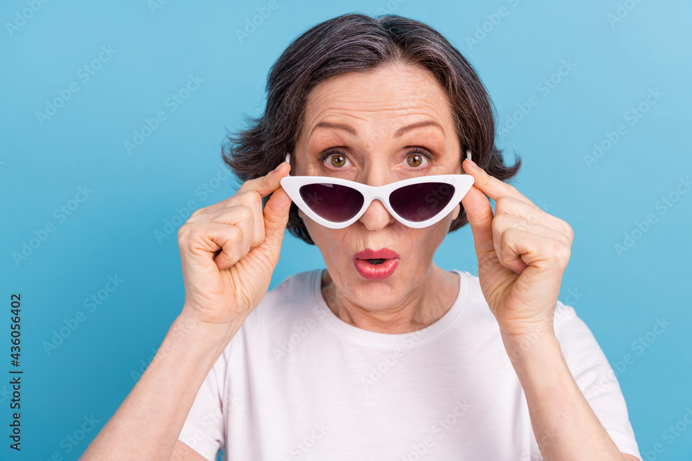 Portrait of attractive amazed woman wearing touching specs news sale reaction isolated over bright blue color background Portrait of attractive amazed woman wearing touching specs news sale reaction isolated over bright blue color background