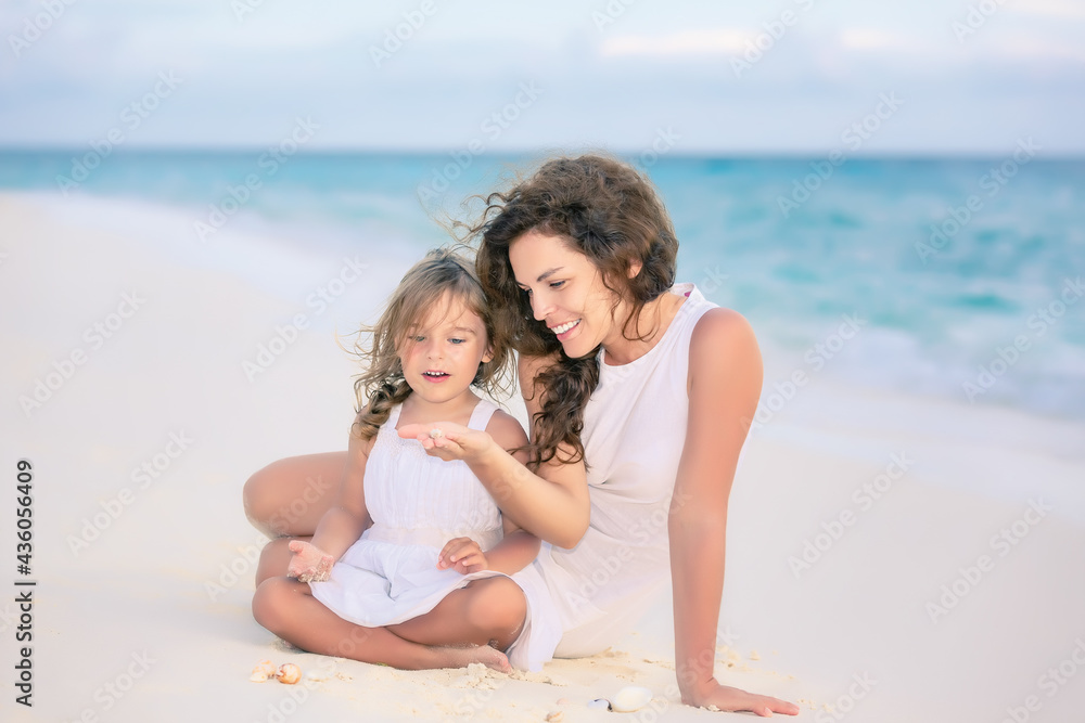 Mother with little daughter playing on ocean beach, Maldives. Family on the beach concept.