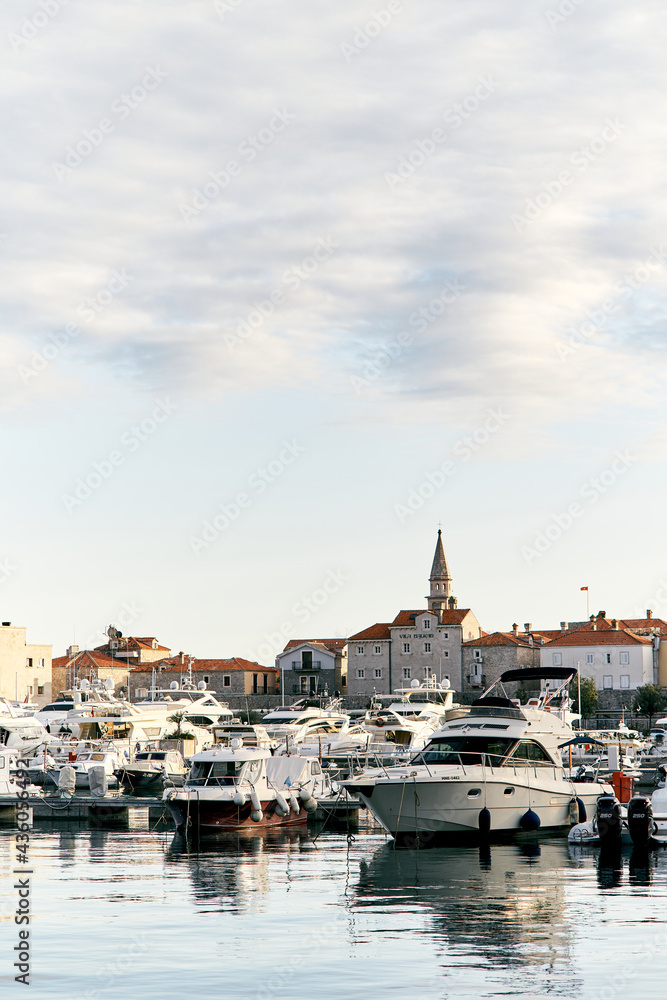 A pier with white yachts against the background of ancient houses and a beautiful cloudy sky