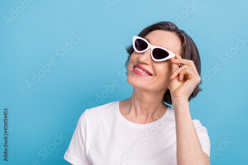 Portrait of attractive cheerful dreamy woman wearing touching specs fantasizing isolated over bright blue color background
