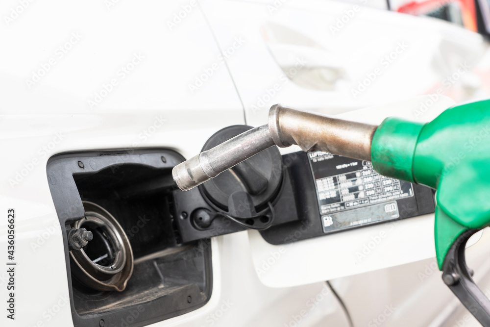 Close up image of green gas pump near hole of car tank ready for refueling car on gas station.