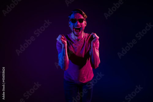 Portrait of attractive cheerful amazed delighted funny guy having fun rejoicing isolated over dark neon purple color background