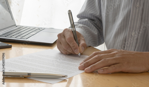 A man sitting signing a contract. Hand of a man writing a document.  photo