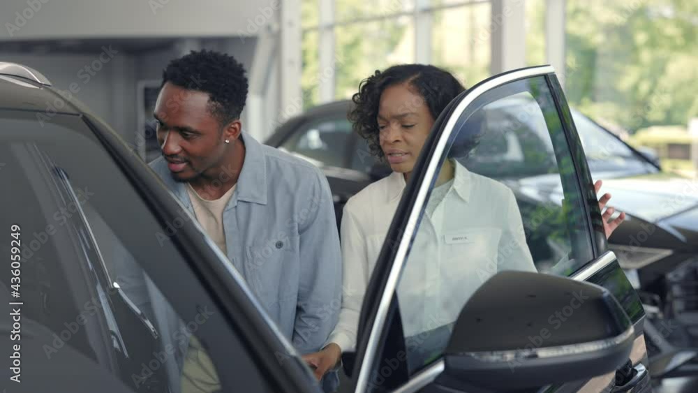Female dealer presenting luxury car for male customer Female dealer presenting luxury car for male customer