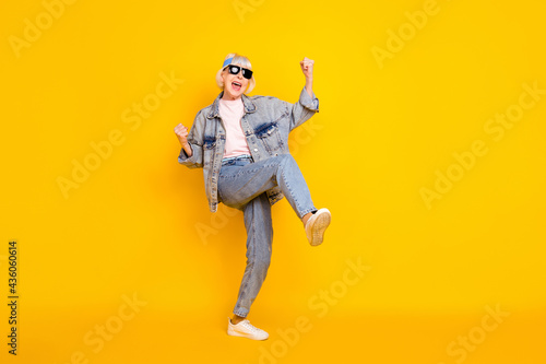 Full length body size view of attractive elderly cheerful woman rejoicing dancing having fun isolated over bright yellow color background