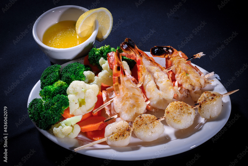 Lobsters and scallops with vegetables dinner, butter and lemon Lobsters and scallops with vegetables dinner, butter and lemon