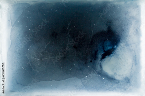 Aerial view of abstract patterns formed by dark blue ice and small cracks within a blue and white frozen ice sheet