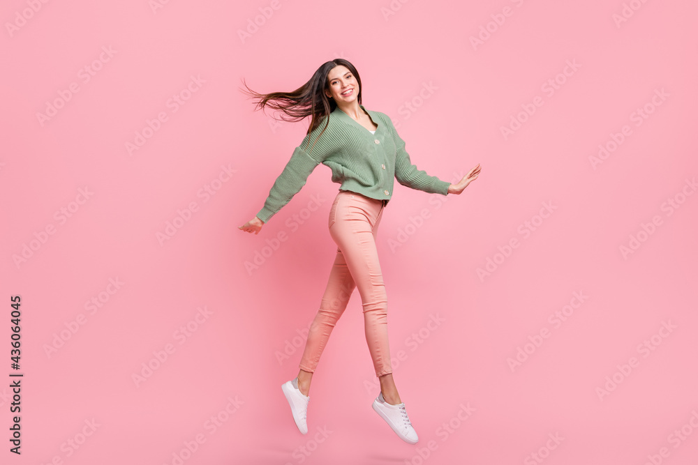 Full body profile portrait of charming young lady jump look camera hair flying isolated on pink color background Full body profile portrait of charming young lady jump look camera hair flying isolated on pink color background