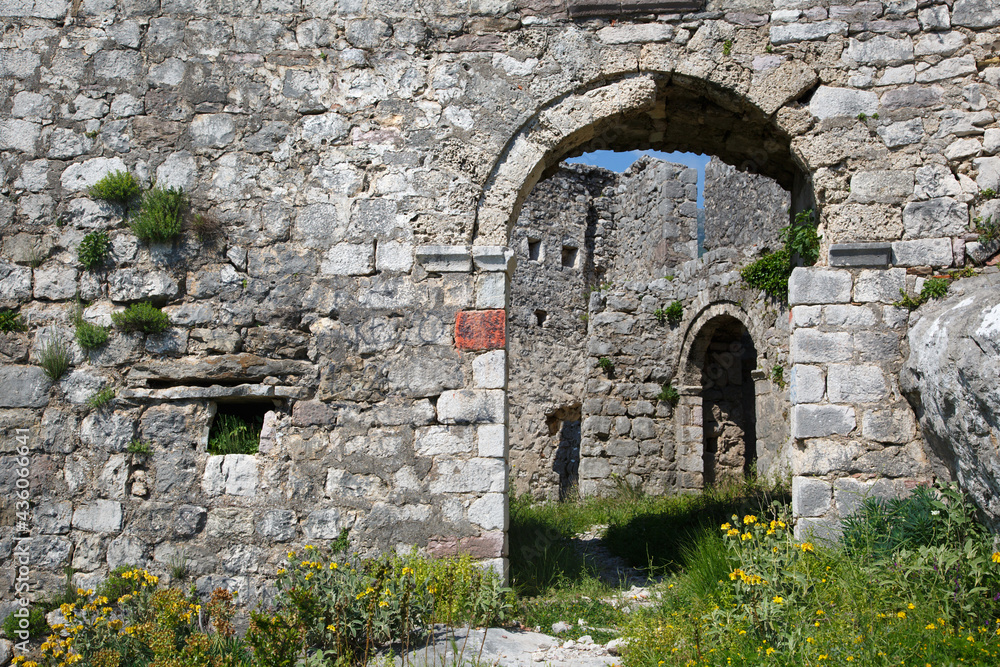 Old stone wall with windows and a doorway.