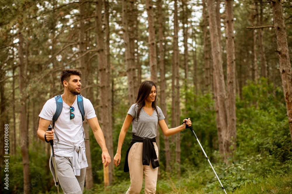 Fototapeta premium Smiling young couple walking with backpacks in the forest