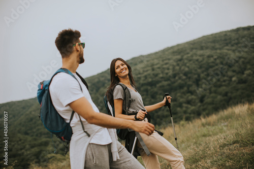 Smiling young couple walking with backpacks on the green hills