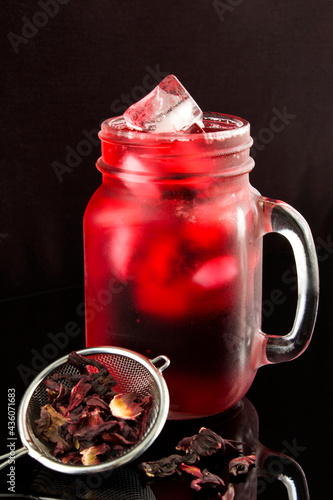 Iced hibiscus or karkade tea in the glass on the black background.Close-up.