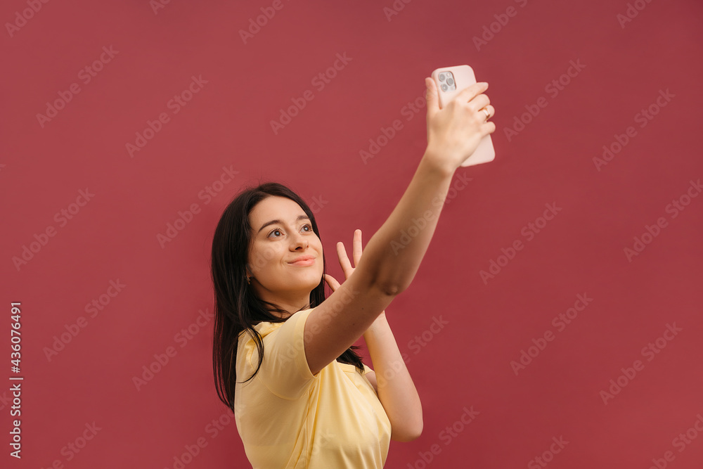 Image of joyful caucasian woman holding cellphone and gesturing ok sign while winking isolated over pink background Image of joyful caucasian woman holding cellphone and gesturing ok sign while winking isolated over pink background