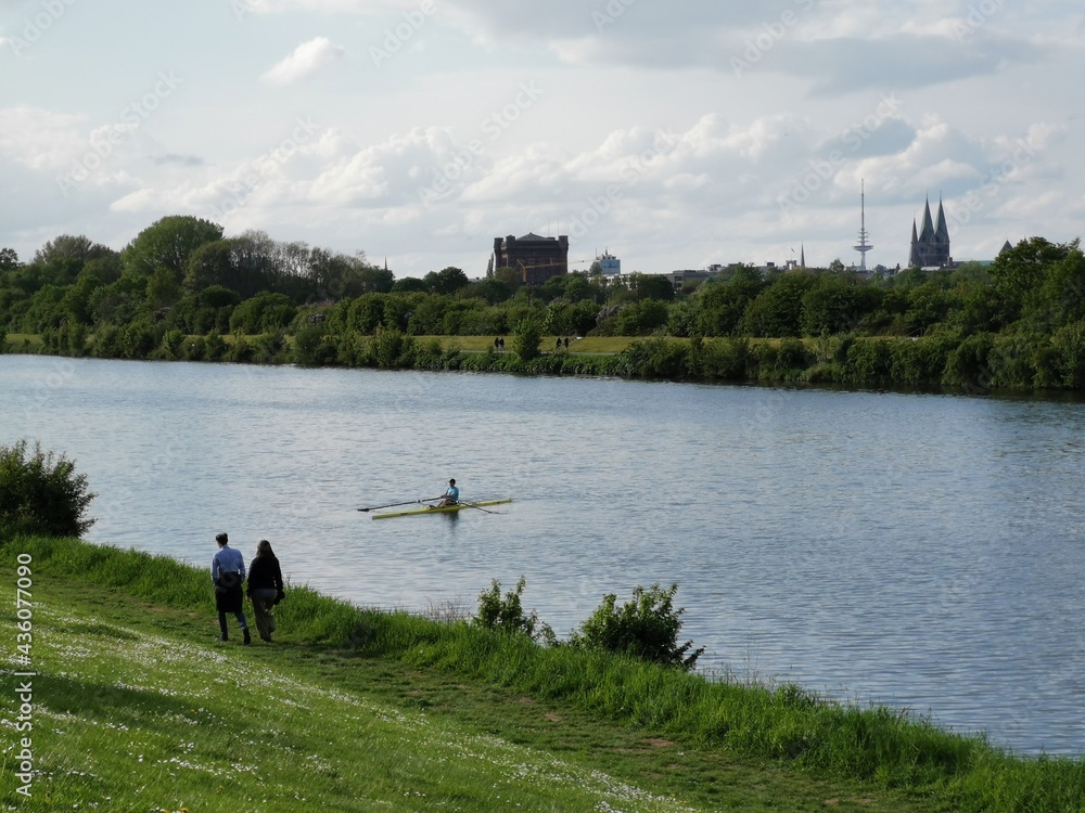 Obraz premium Bremen-Neustadt, Germany - May 16 2021: Lake Werdersee in sunny spring weather. Sights in background: Dom, Umgedrehte Kommode, Television tower Walle. Rowing boat track in foreground.