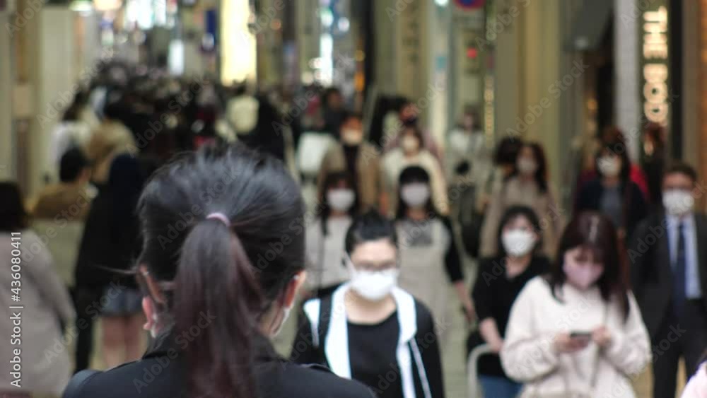 OSAKA, JAPAN - APRIL 2021 : Crowd of people wearing surgical masks to protect from Coronavirus (COVID-19) at in busy rush hour. View around Namba, Shinsaibashi downtown shopping street. OSAKA, JAPAN - APRIL 2021 : Crowd of people wearing surgical masks to protect from Coronavirus (COVID-19) at in busy rush hour. View around Namba, Shinsaibashi downtown shopping street.