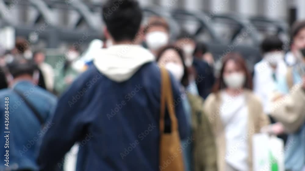 OSAKA, JAPAN - APRIL 2021 : Crowd of people wearing surgical masks to protect from Coronavirus (COVID-19) at the street in busy rush hour. View of commuters after work around Osaka train station. OSAKA, JAPAN - APRIL 2021 : Crowd of people wearing surgical masks to protect from Coronavirus (COVID-19) at the street in busy rush hour. View of commuters after work around Osaka train station.