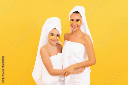 moisturizing skin. cosmetology. mom and daughter in terry towel use patch. beauty day in family spa.