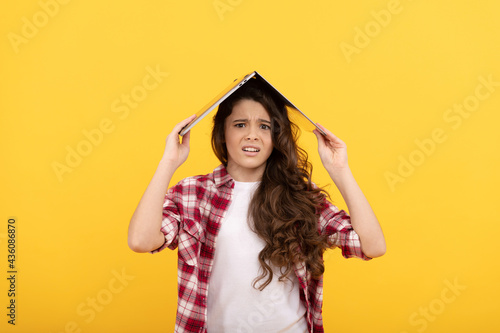 Unhappy school girl worry holding laptop computer on head for distance education, telelearning