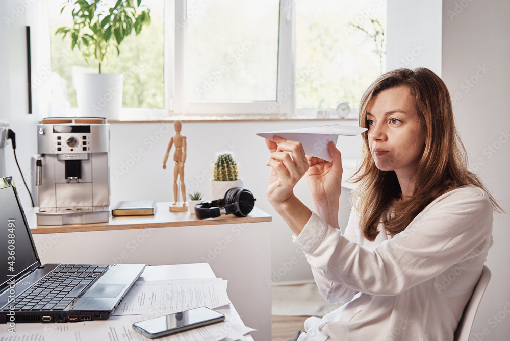 Woman procrastinate at workplace. Freelancer on remote work at home office. Unmotivated tired woman play with paper plain. Lazy office worker Woman procrastinate at workplace. Freelancer on remote work at home office. Unmotivated tired woman play with paper plain. Lazy office worker