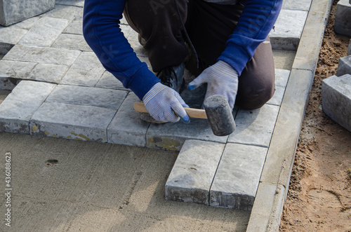 Construction of pavement near the house. Bricklayer places concrete paving stone blocks for building up a Sidewalk pavement