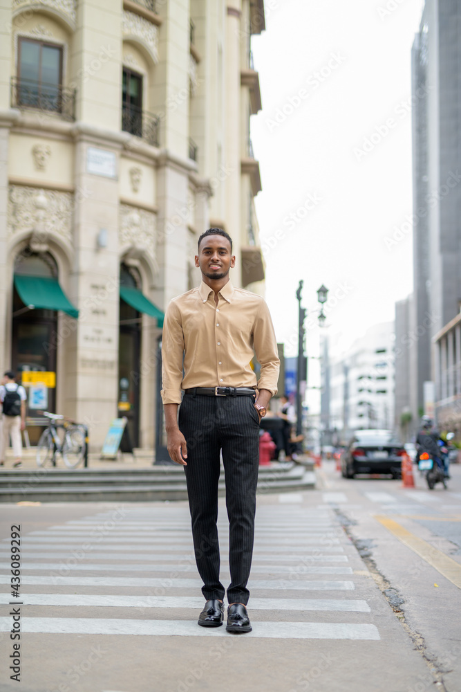 Full length shot of African businessman smiling outdoors in city