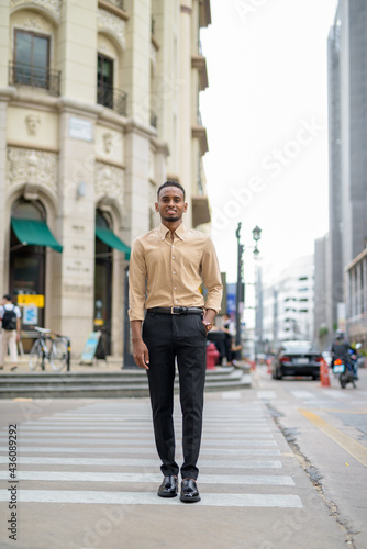 Full length shot of African businessman smiling outdoors in city