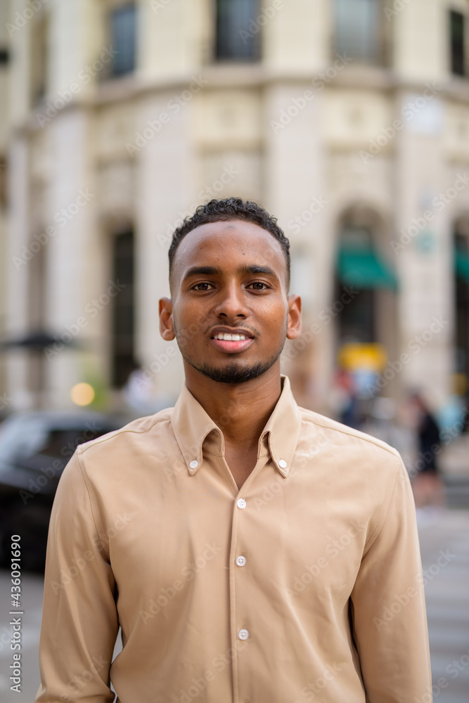 Happy black young African businessman smiling outdoors in city