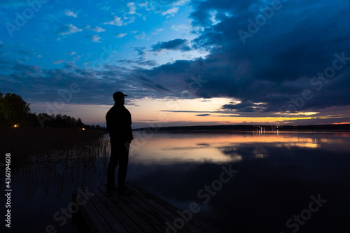 Russia. May 16, 2021. The figure of a man on the pier on the Sukhodolsky lake before dawn. © yurisuslov