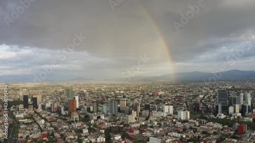 Aerial drone view over business and financial district of Mexico City, with skyscrapers and cityscape of Paseo de la Reforma, on a dramatic cloudy day with a rainbow, during the golden hour