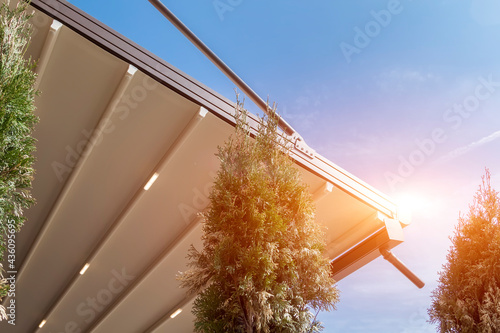canvas awning with metal frame and drainage pipe against blue sunny sky. modern shading for house photo