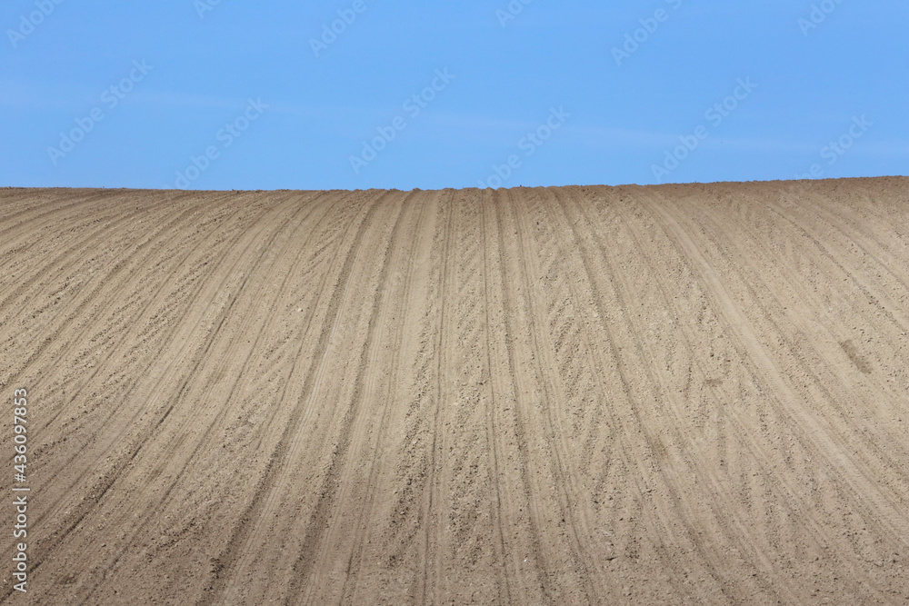 Naklejka premium Landscape agricultural land in slope recently plowed for the crop