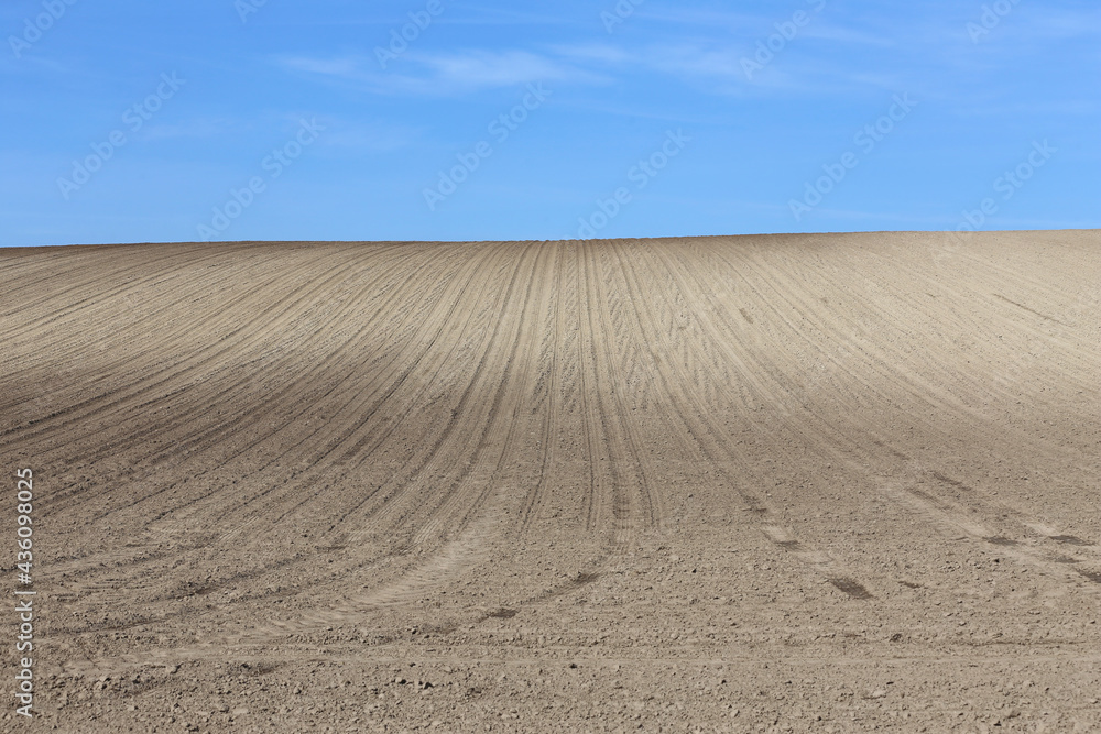 Naklejka premium Plowed cultivated agricultural land field at springtime rural landscape as a background