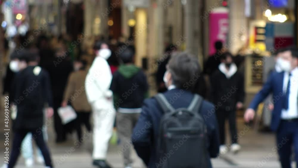 OSAKA, JAPAN - APRIL 2021 : Crowd of unidentified people wearing surgical masks to protect from Coronavirus (COVID-19) at busy downtown street. Slow motion shot. Focus in front. OSAKA, JAPAN - APRIL 2021 : Crowd of unidentified people wearing surgical masks to protect from Coronavirus (COVID-19) at busy downtown street. Slow motion shot. Focus in front.