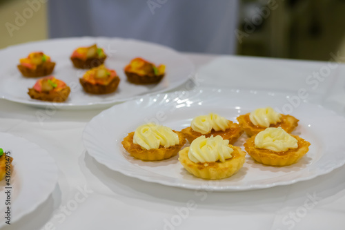 Assortment of delicious fresh shortcrust tart cakes with cream on white plate for sale at restaurant, cafe, bakery. Dessert, culinary, sweet food and confectionery concept
