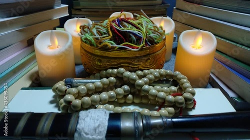 Yellow candlelight was swaying amid the surrounding prayer books.  There is a necklace of yellow rosary and black sheath giving the idea of ​​the occult prayer.  photo