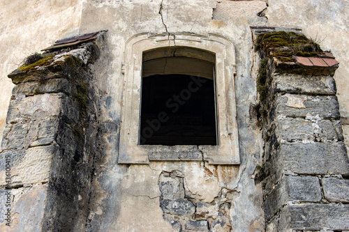 A window in the wall of a historic building. Damaged facade of the chapel in the cemetery.
