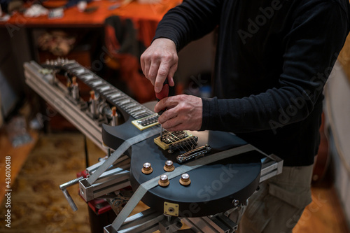 Electrical guitar in repair service shop with a hands of a guitar luthier