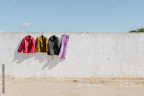 colorful clothes drying in the sun hanging against the white wall