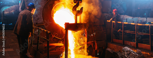 Cast iron, blast furnace in foundry, liquid molten metal pouring in ladle, metallurgical factory, horizontal banner image.