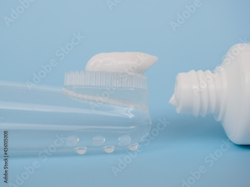 children's silicone tooth brush and paste on a blue background close-up, toothbrush on the finger