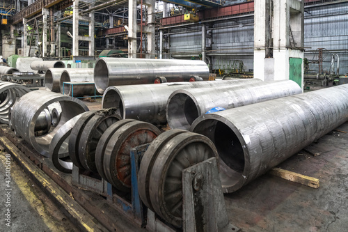 Pipe factory production line with steel tubular pipes on floor, metalwork heavy industry.