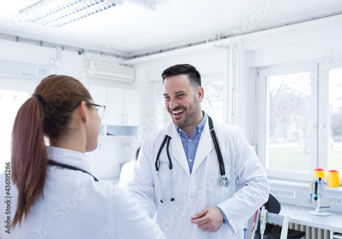 Two doctors greeting smiling wearing lab coats.