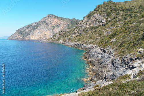 Rocky coastline with turquoise and clear sea water surface at sunny day. Summer holiday and travel to sea