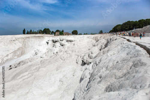 Group of tourists in the carbonate mineral cliff with calcite-laden waters in Hierapolis Pamukkale in Turkey.