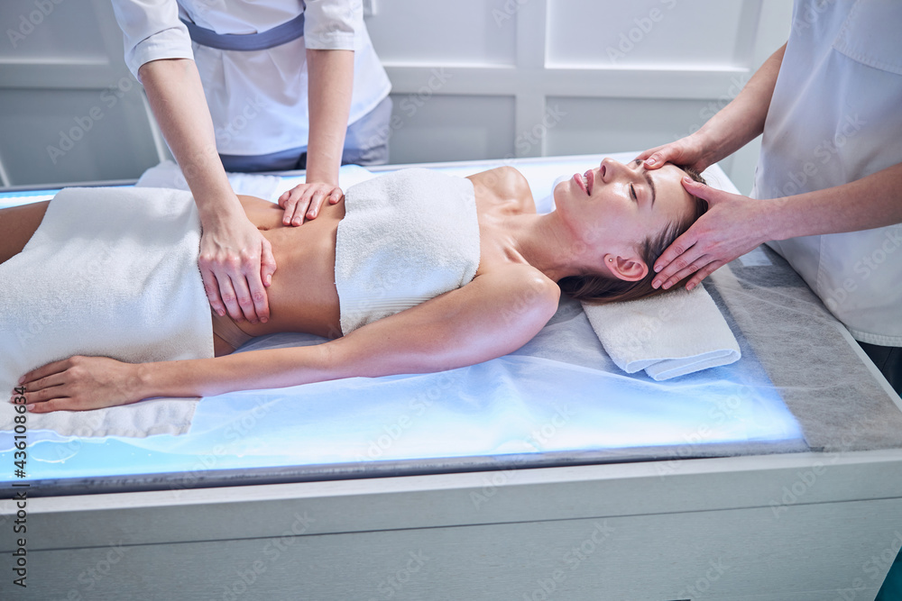 Fototapeta premium Beautiful elegant female relaxing at a spa day while getting hand massage in spa salon