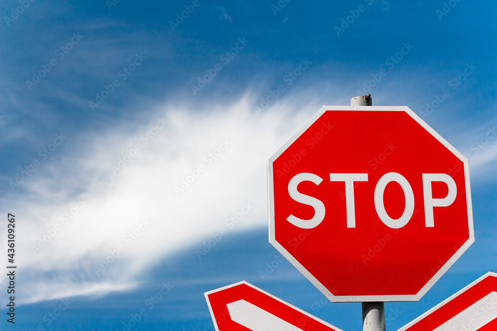 Obraz premium Bright red STOP sign on the road in front of the railway crossing