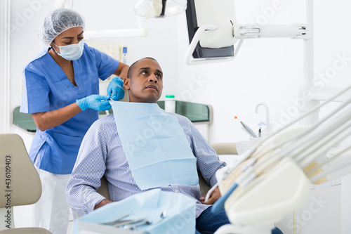 Dental assistant prepares the patient for surgery